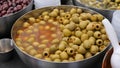 Green Spanish pitted olives in brine in container for sale.