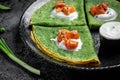 Green spinach crepes or pancakes with smoked salmon and sour cream on black plate, dark background, Food recipe Royalty Free Stock Photo
