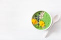 Green spinach smoothie bowl with blueberry, chia seed and edible pansy flowers