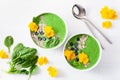 Green spinach smoothie bowl with blueberry, chia seed and edible pansy flowers