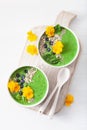 Green spinach smoothie bowl with blueberry, chia seed and edible pansy flowers