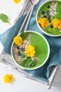 Green spinach smoothie bowl with blueberry, chia seed and edible pansy flowers