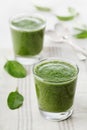 Green spinach smoothie in glass on white table Royalty Free Stock Photo