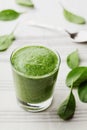 Green spinach smoothie in glass on white table Royalty Free Stock Photo