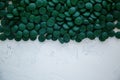 Green spirulina pills on a white background