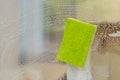 Green sponge scrubbing soapy glass surface for cleaning Royalty Free Stock Photo