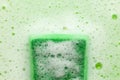 Green sponge in soapy foam. Washing dishes, house cleaning Royalty Free Stock Photo