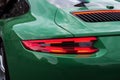 Green sports car with red backlight on. Closeup.