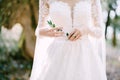 Green sprig in the hands of a bride in a white embroidered dress. Close-up Royalty Free Stock Photo