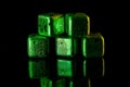 Green Stainless steel cubes simulating ice for cooling drinks on a black surface with a reflection