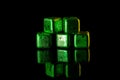 Green Stainless steel cubes simulating ice for cooling drinks on a black surface with a reflection