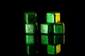 Green Stainless steel cubes simulating ice for cooling drinks on a black surface with a reflection