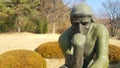 Green statue of thinker Auguste Rodin, setting naked on a rock Royalty Free Stock Photo