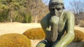 Green statue of thinker Auguste Rodin, setting naked on a rock Royalty Free Stock Photo