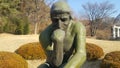 Green statue of thinker Auguste Rodin, setting naked on a rock Royalty Free Stock Photo