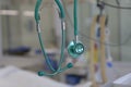 Green stethoscope, on background patient  connected to medical ventilator in ICU in hospital, a place where can be treated Royalty Free Stock Photo