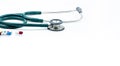 Green stethoscope and capsule pills on white background. Health checkup. Cardiology doctor equipment for heartbeat test.