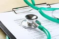 Green stethoscope lying on a medical record