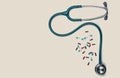 Green stethoscope with pile of capsule pills on white background with copy space. Medical tool for doctor. Health check