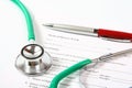 Green stethoscope and a red pen lying on a medical history form Royalty Free Stock Photo