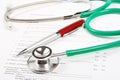 Green stethoscope and a red pen lying on a medical history form Royalty Free Stock Photo