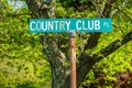 Green street sign with white letters that says Country Club PL