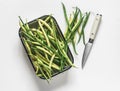 Green string beans in a vintage enameled tray on a light background, top view