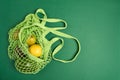 Green string eco shopping bag with vegatables avocado, lemon on green background Royalty Free Stock Photo