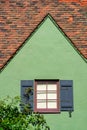 Green stucco house exterior with dark shades and red accent paint with brown adobe roof tiles in afternoon sun in Royalty Free Stock Photo