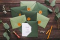 Green stylish envelopes with wedding postcards on wood