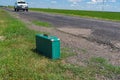 Green suitcase lonely standing on a country roadside at summer season
