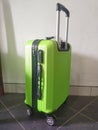 A green suitcase with a rough pattern is ready to be taken away