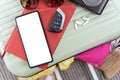 A green suitcase sits on a table. On top of the suitcase is a cell phone, car keys, sunglasses, earbuds, and a camera. The earbuds Royalty Free Stock Photo