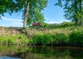 Summer landscape with a small river, brown sofa on the shore, beautiful reflections in the water, summer river reflection