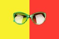 Green sunglasses yellow and red background close up top view  fashion woman sunshades on colorful backdrop Royalty Free Stock Photo