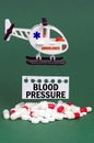 On a green surface, an ambulance helicopter, pills and a white sign with the inscription - Blood Pressure Royalty Free Stock Photo