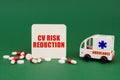 On a green surface, an ambulance, pills and a sign with the inscription - CV Risk Reduction