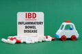 On a green surface, an ambulance, pills and a white sign with the inscription - Inflammatory Bowel Disease