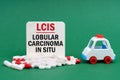 On a green surface, an ambulance, pills and a white sign with the inscription - Lobular Carcinoma In Situ