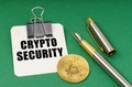 On a green surface, a bitcoin coin, a pen and a sheet of paper with the inscription - Crypto security