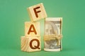 On a green surface, dollars and cubes with the inscription - FAQ