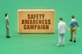 On the green surface are figures of people and a sign with the inscription - Safety Awareness Campaign Royalty Free Stock Photo