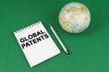 On a green surface lies a model of the planet and a notepad with the inscription - Global Patents