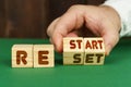 On a green surface, a man puts cubes with the inscription - RESTART, RESET