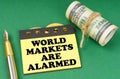 On a green surface are a pen, dollars and yellow stickers with the inscription - World markets are alarmed Royalty Free Stock Photo