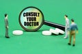 On a green surface are pills, miniature figures of people and a magnifying glass with the inscription - Consult doctor Royalty Free Stock Photo