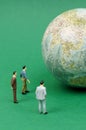 On the green surface is a planet around which there are figures of people. Royalty Free Stock Photo