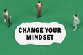 On the green surface there are figures of businessmen and there is torn paper with the inscription - Change Your Mindset