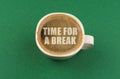 On a green surface there is a white cup with coffee, on the coffee foam there is an inscription - Time for a Break Royalty Free Stock Photo
