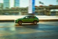 Green SUV car in motion. Porsche Macan is driving on the highway, side view. First generation of German crossover car